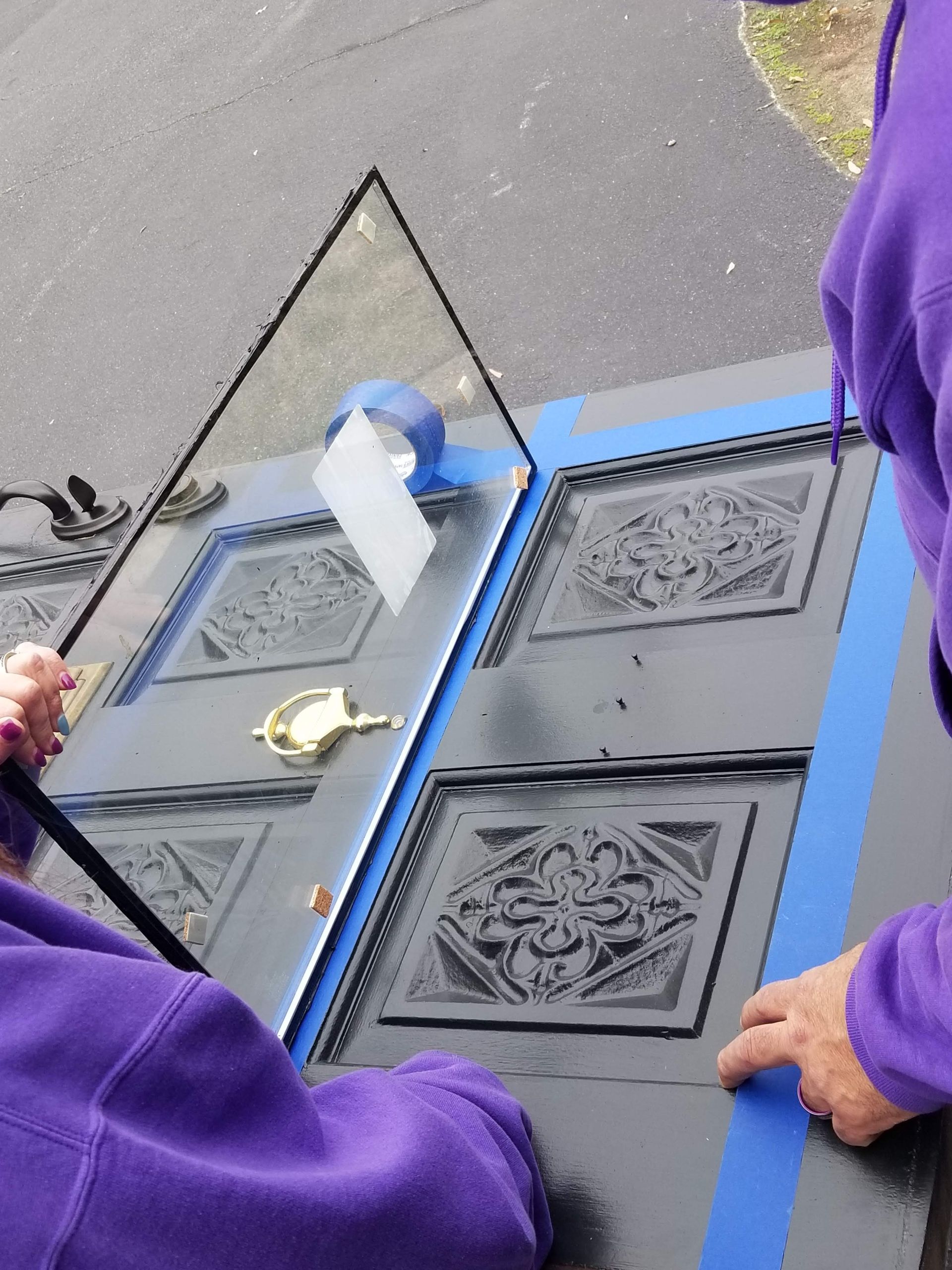 A person in a purple shirt is working on a piece of glass