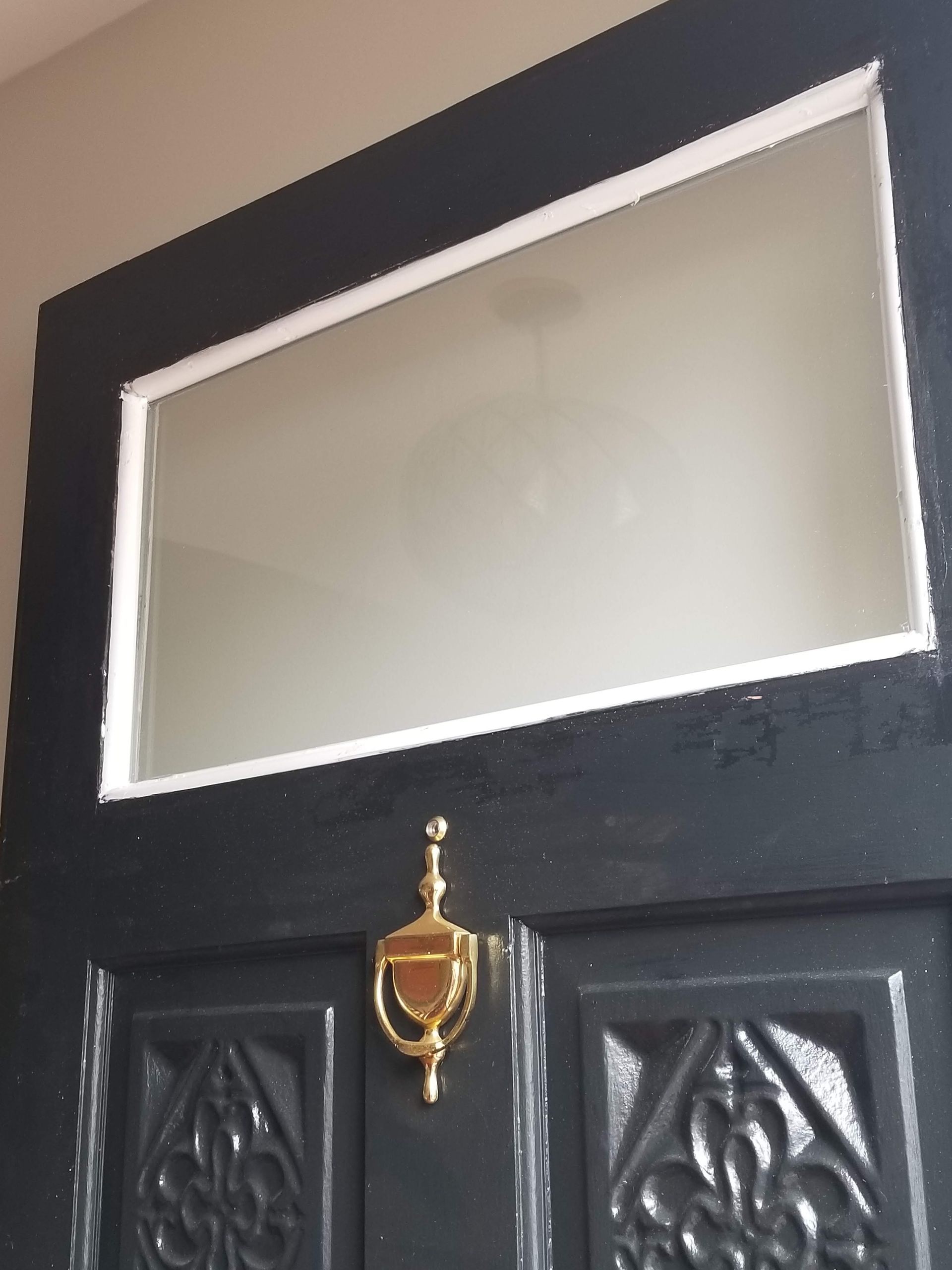 A black door with a gold door knocker on it