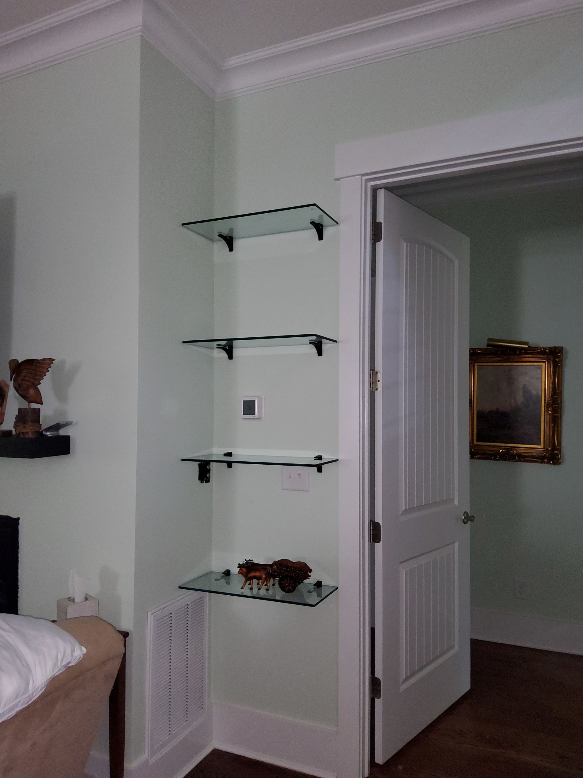 A bedroom with glass shelves and a painting on the wall