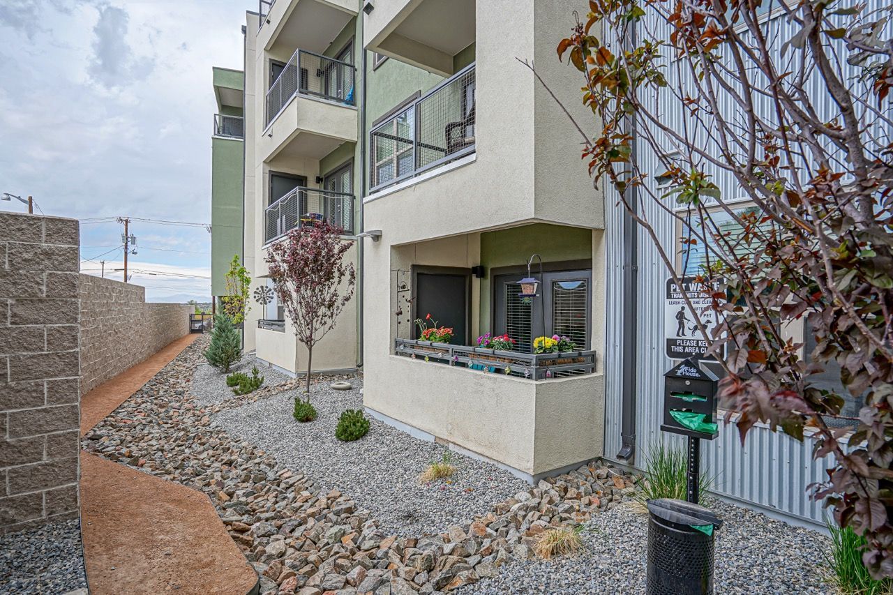 Exterior view of a multi-story apartment building with balconies and a small front patio.