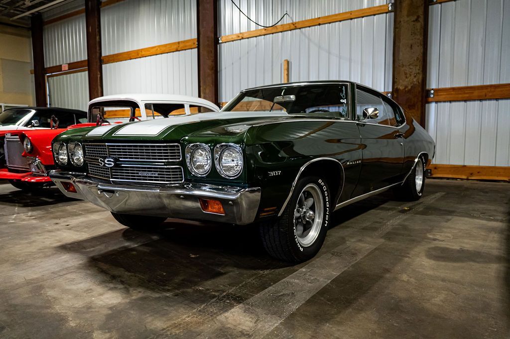 Green 1970 Chevrolet Chevelle SS muscle car with white racing stripes, parked in a garage.