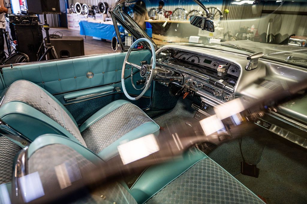 Teal and silver classic car interior with a steering wheel and detailed dashboard.