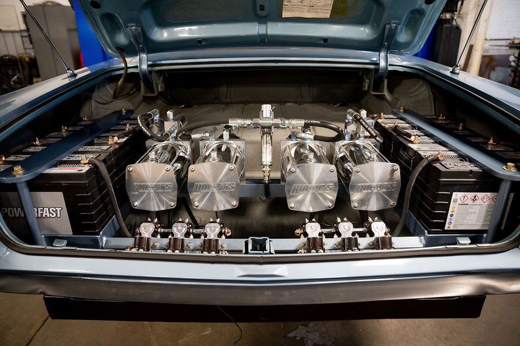 Blue car trunk with hydraulic suspension system and multiple batteries installed.