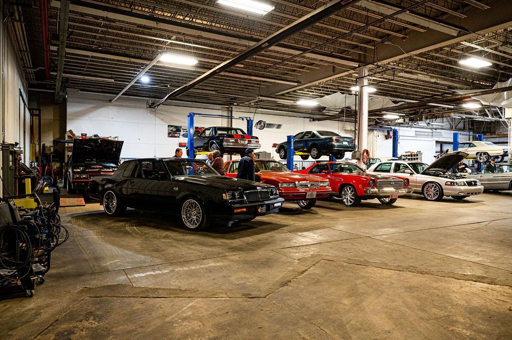 Inside auto repair shop filled with cars on lifts and waiting for service.