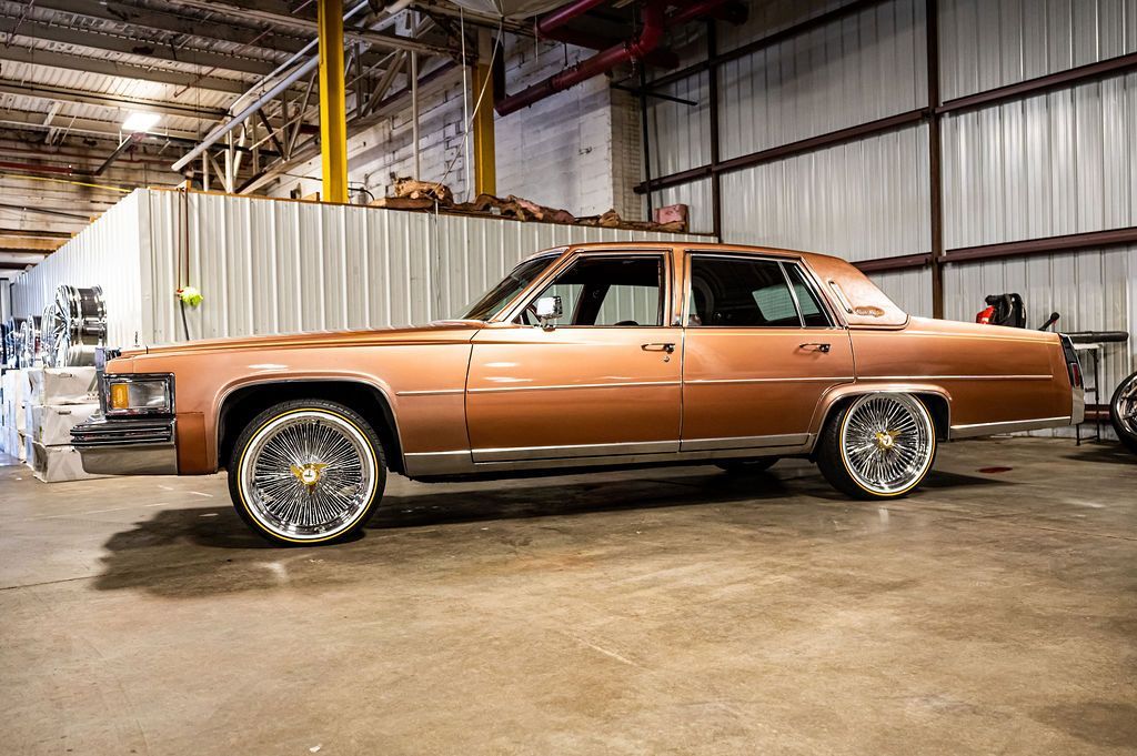 Brown classic car with large custom rims in a garage.