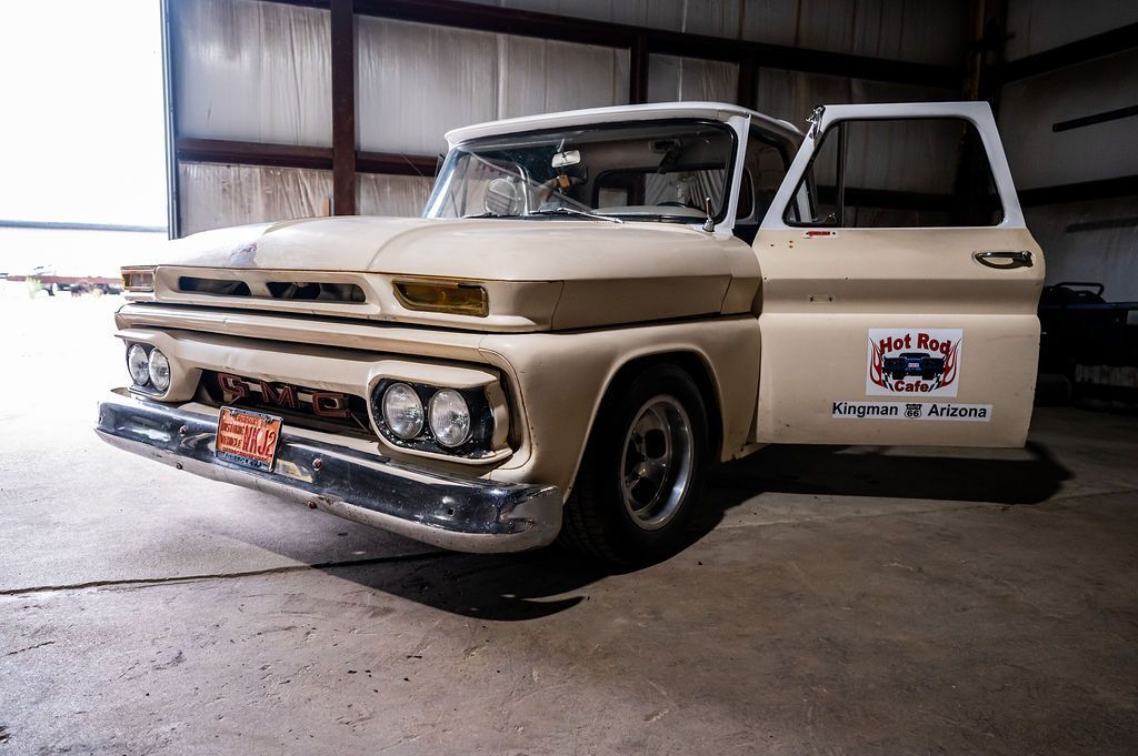 Cream-colored vintage pickup truck with door open, parked inside a garage.