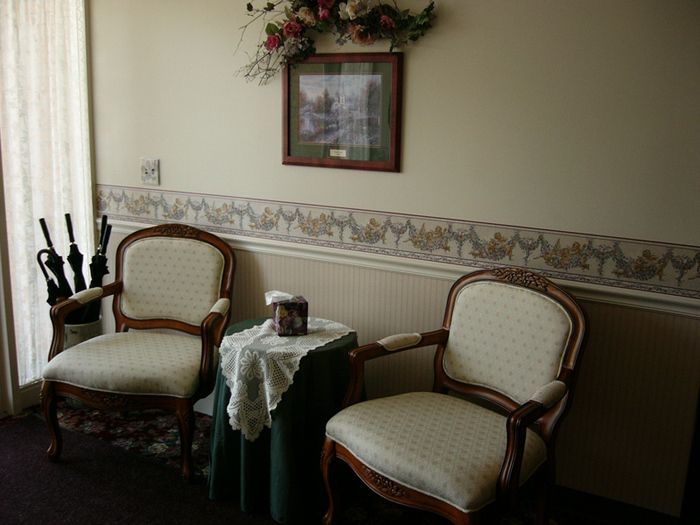 Two chairs and a table in a room with a picture on the wall