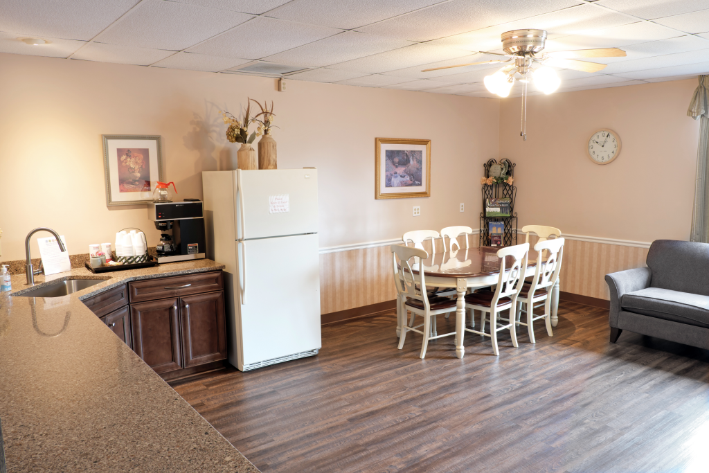 A kitchen with a refrigerator , dining table , chairs and a couch.