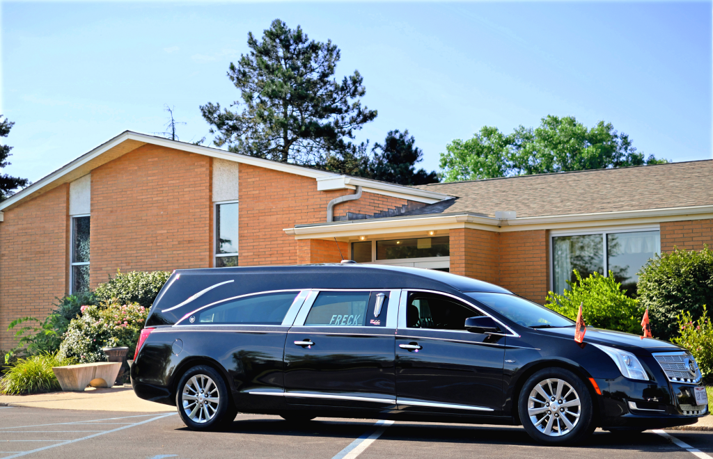 A black limousine is parked in front of a brick building.