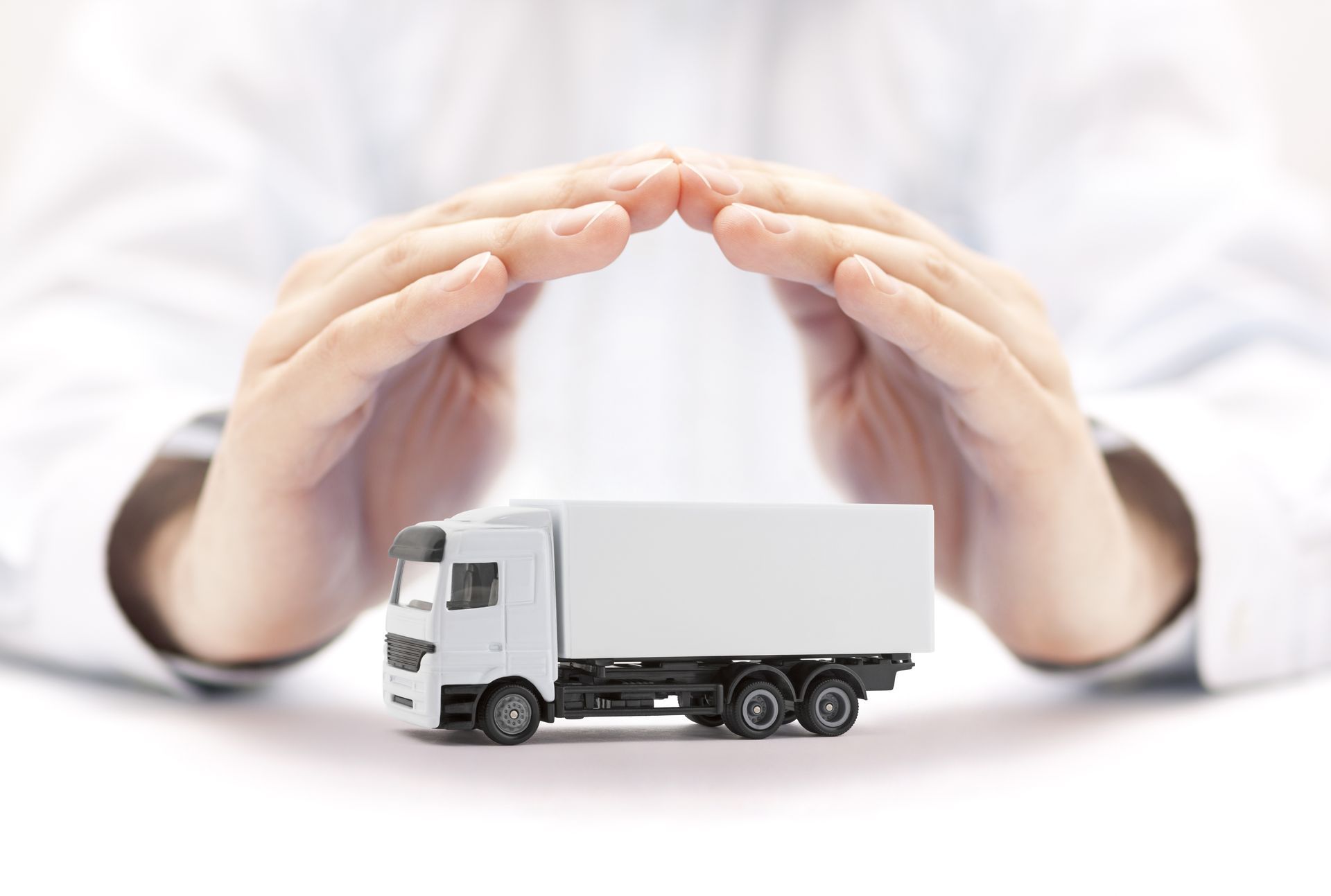 Hands protecting toy truck symbolizing commercial fleet and cargo transport insurance coverage. Hands protecting toy truck symbolizing commercial fleet and cargo transport insurance coverage.
