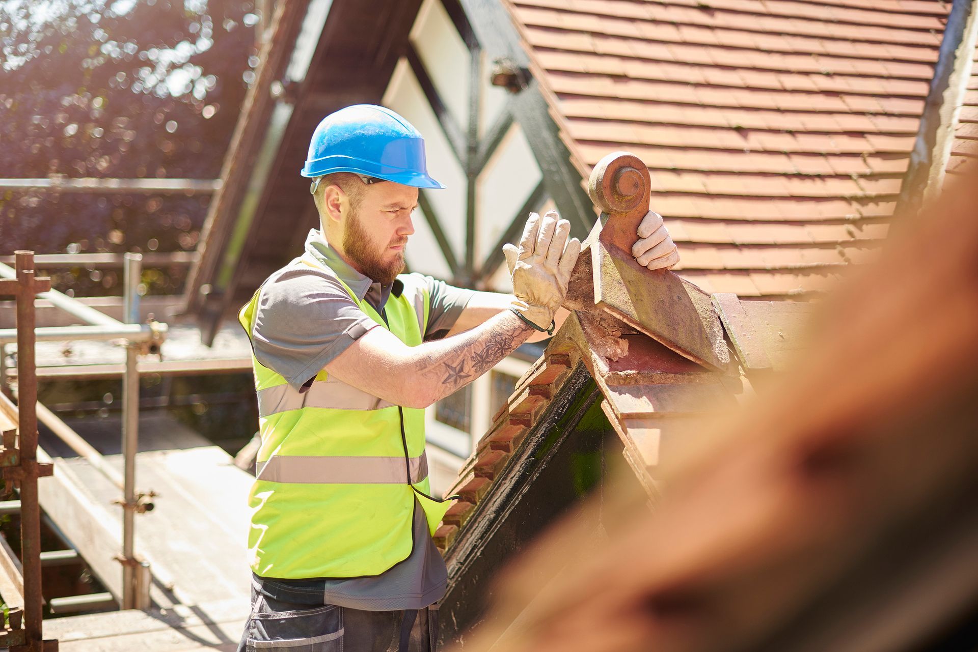 Worker with contractor’s insurance, wearing safety gear and performing work on a roof.