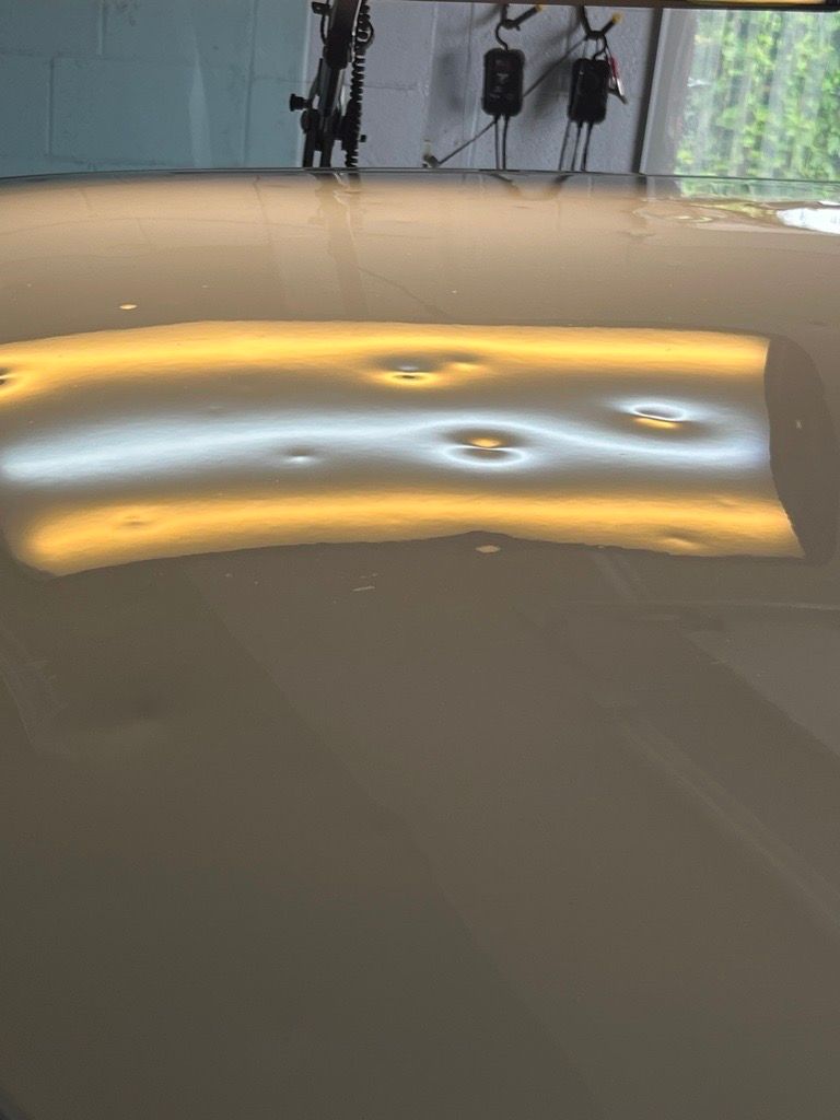 A car's metallic surface reflecting dents under a specialized light, revealing damage before repair.