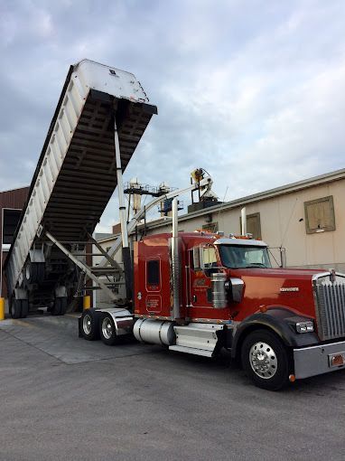 A red GFI Transport dump trailer semi truck is parked in front of a building.