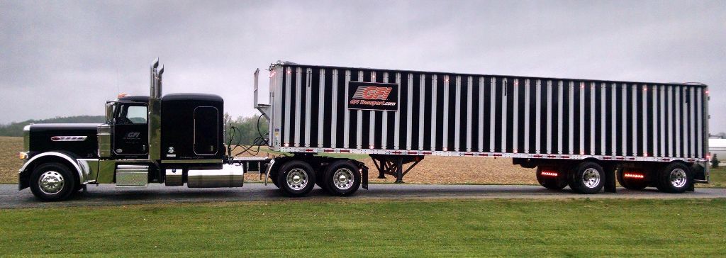 A semi truck is driving down a road with a trailer attached to it from GFI Transport.