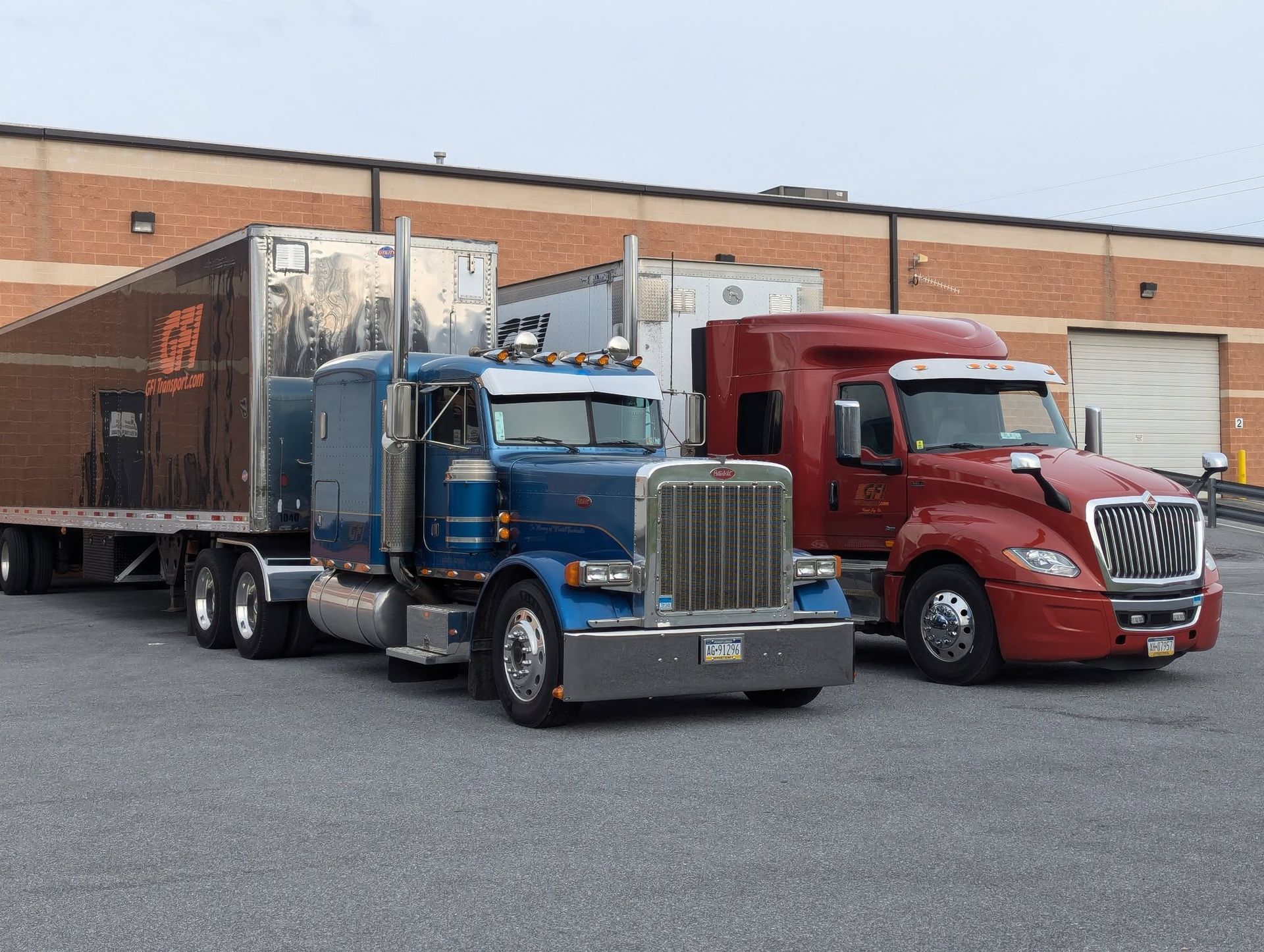 GFI Transport's blue and red semi-trucks parked in front of a brick building ready to haul crushed glass.