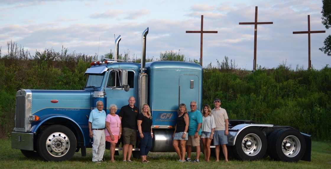 A group of people standing in front of a blue semi truck.