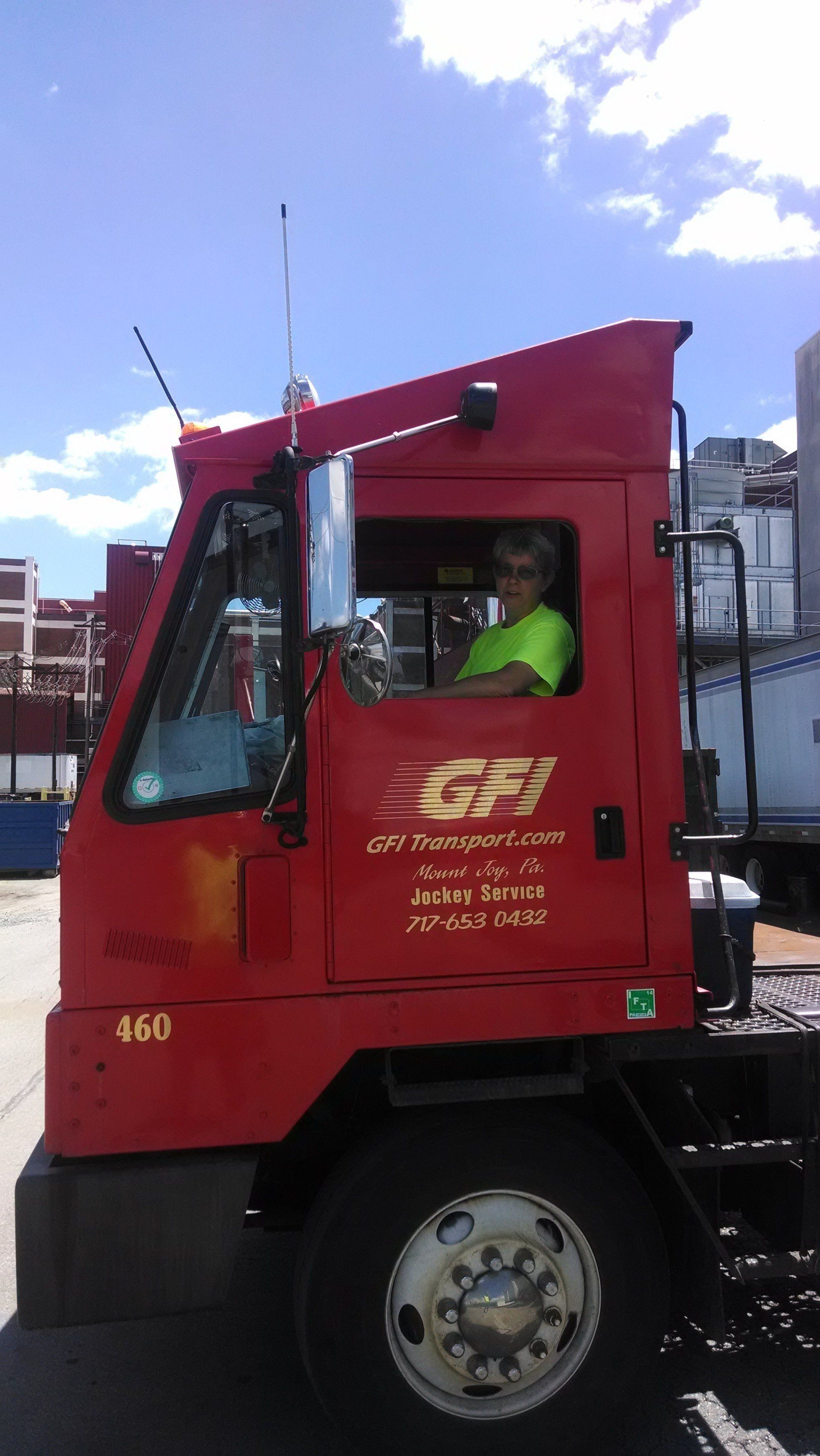 A woman yard or truck jockey is sitting in the driver 's seat of GFI Transport truck