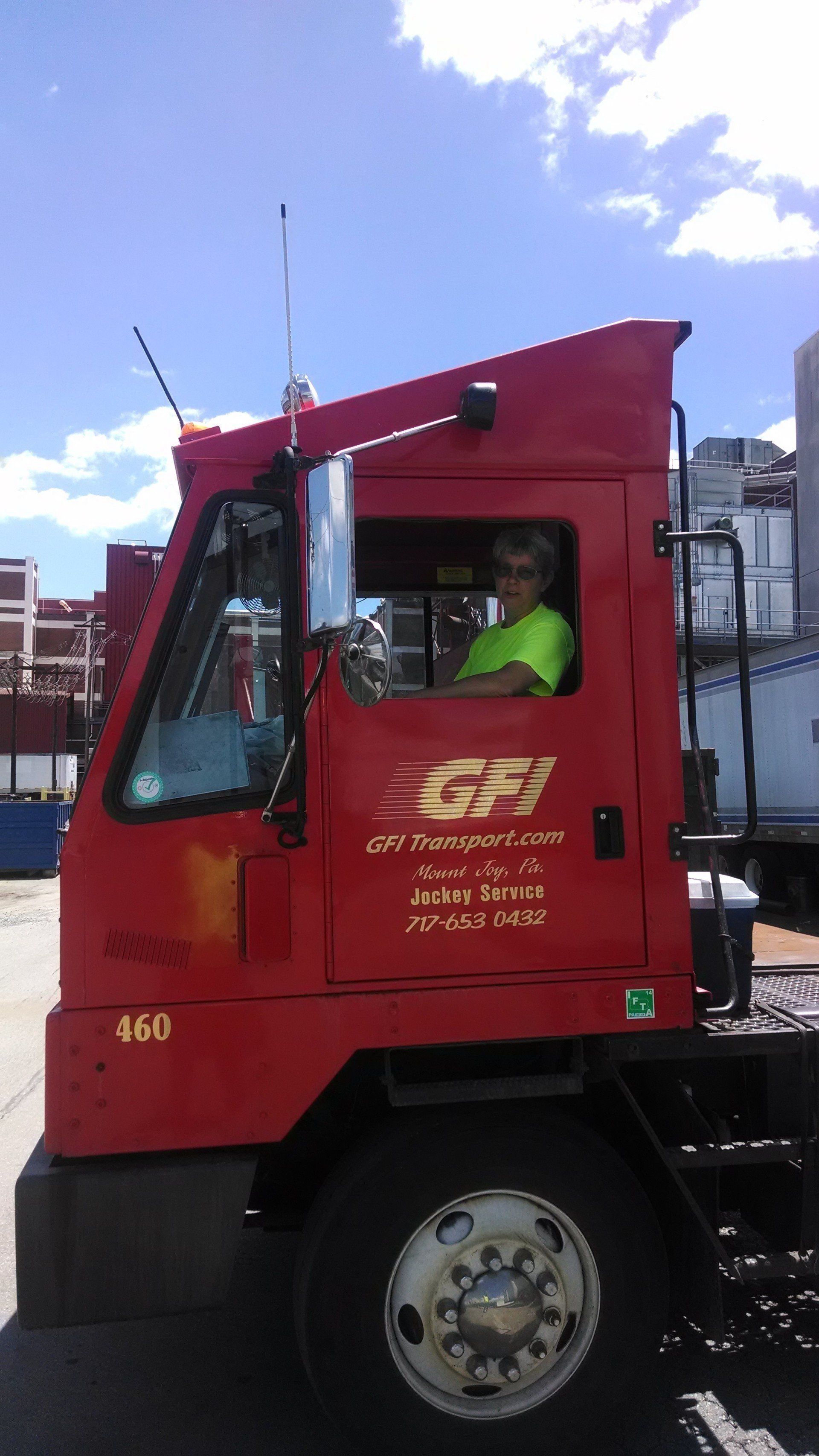 a man is sitting in the driver 's seat of a red GFI Transport truck