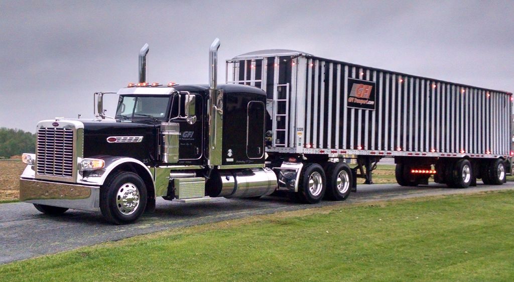 A semi truck is driving down a road with a trailer attached to it from GFI Transport.
