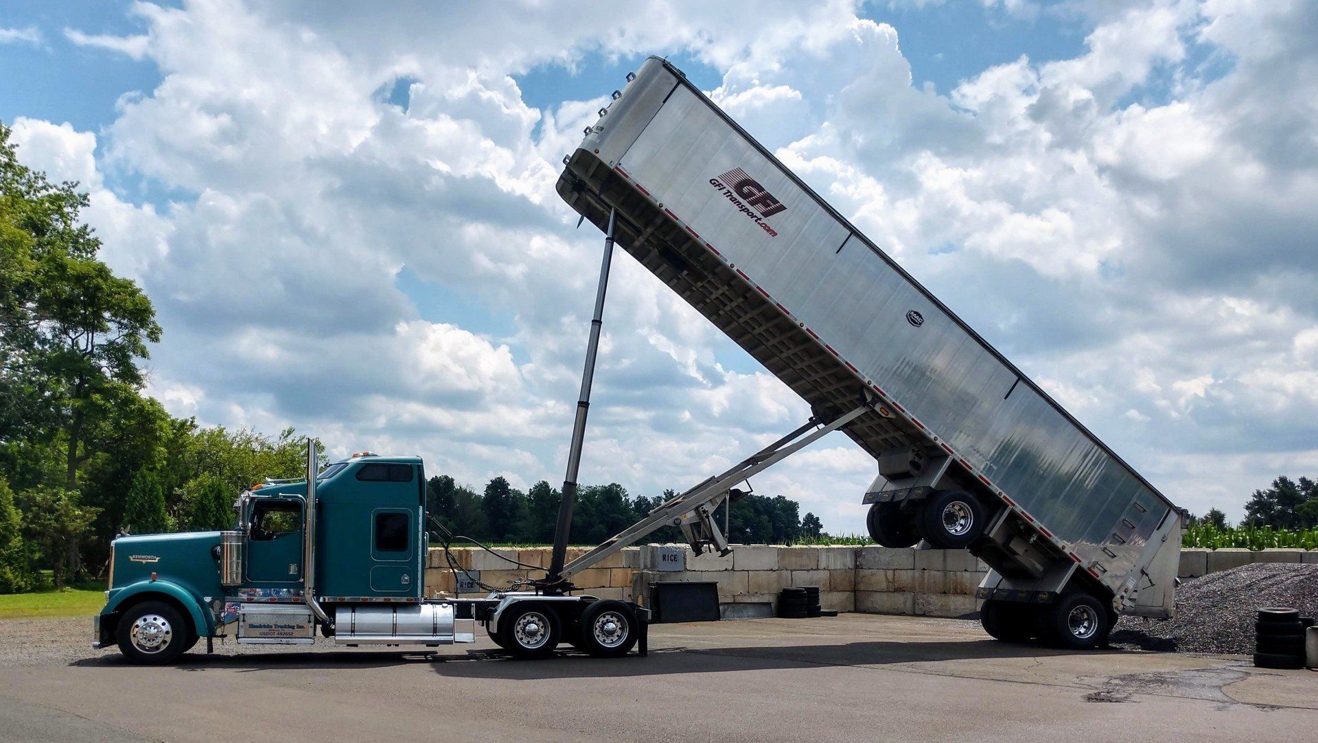 A semi truck is being loaded with a dump trailer.