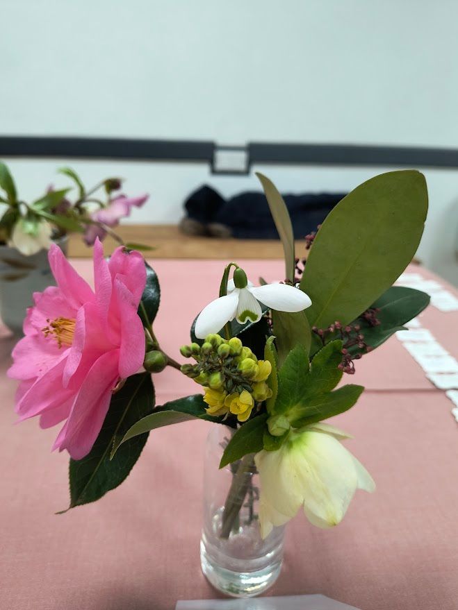 Photo shows pink camellia, cream hellebore, snowdrop, mahonia and skimmia in glass vase.  3rd prizewinner Margaret W