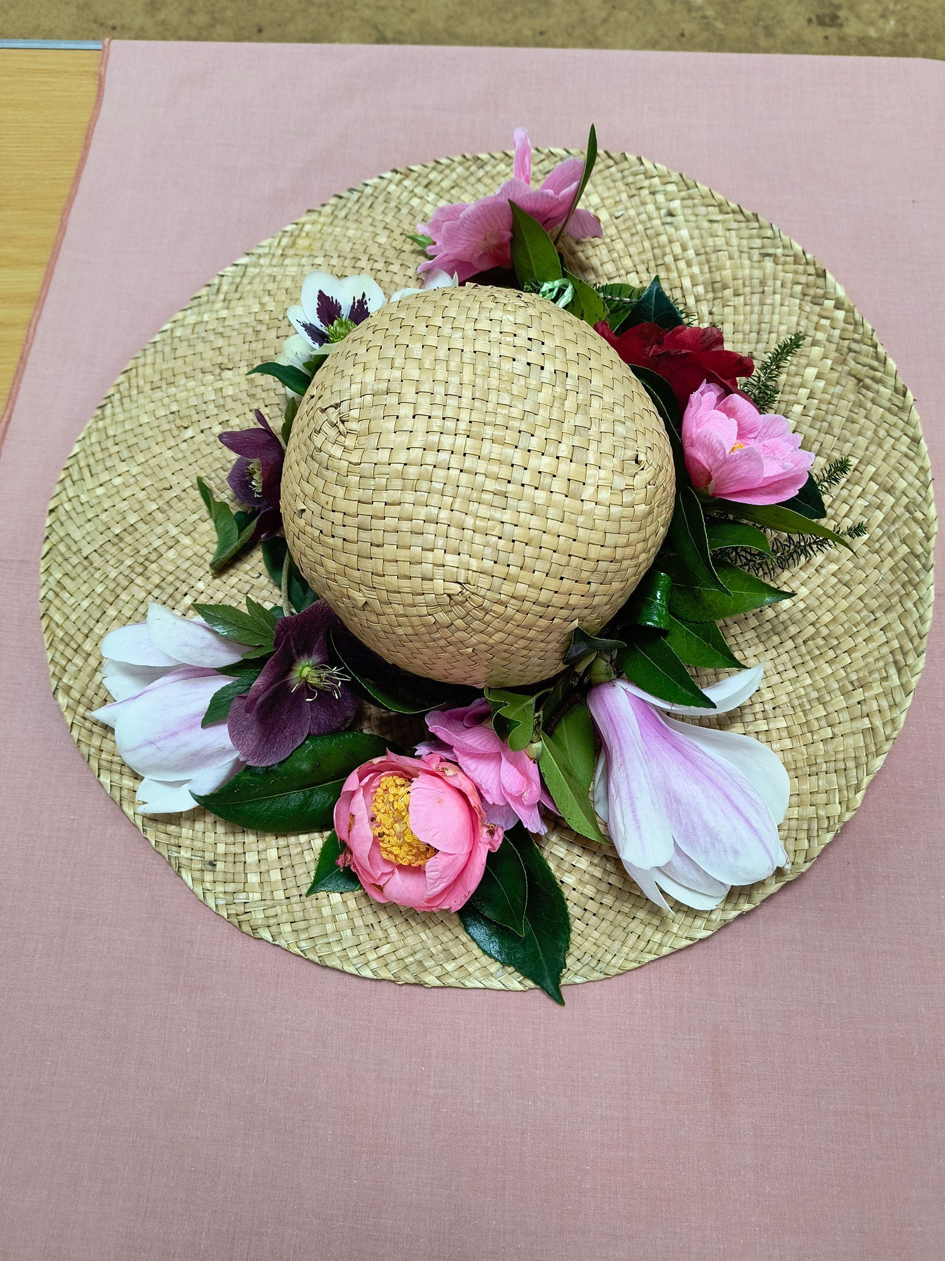 Photo shows a straw hat deocrated with a variety of flowers