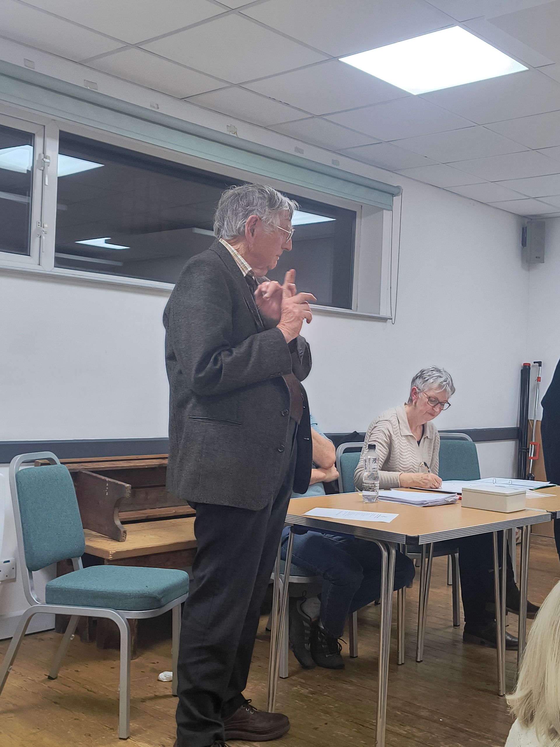Doug Glading stands on the stage to propose Glenn be re-elected as Chair