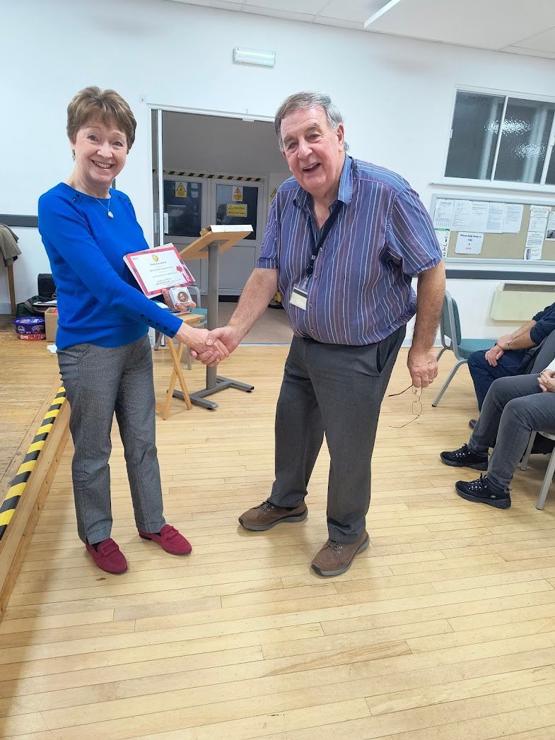 Photo of Club Chair Glenn shaking hands with Lorraine who is holding a certficate and Banksian Medal