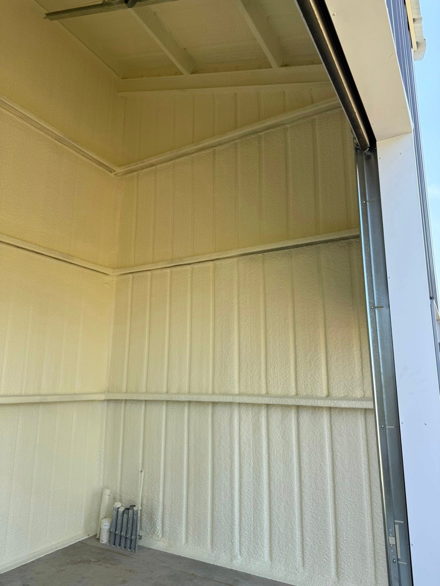 Interior of a building with light yellow spray foam insulation on walls and ceiling.