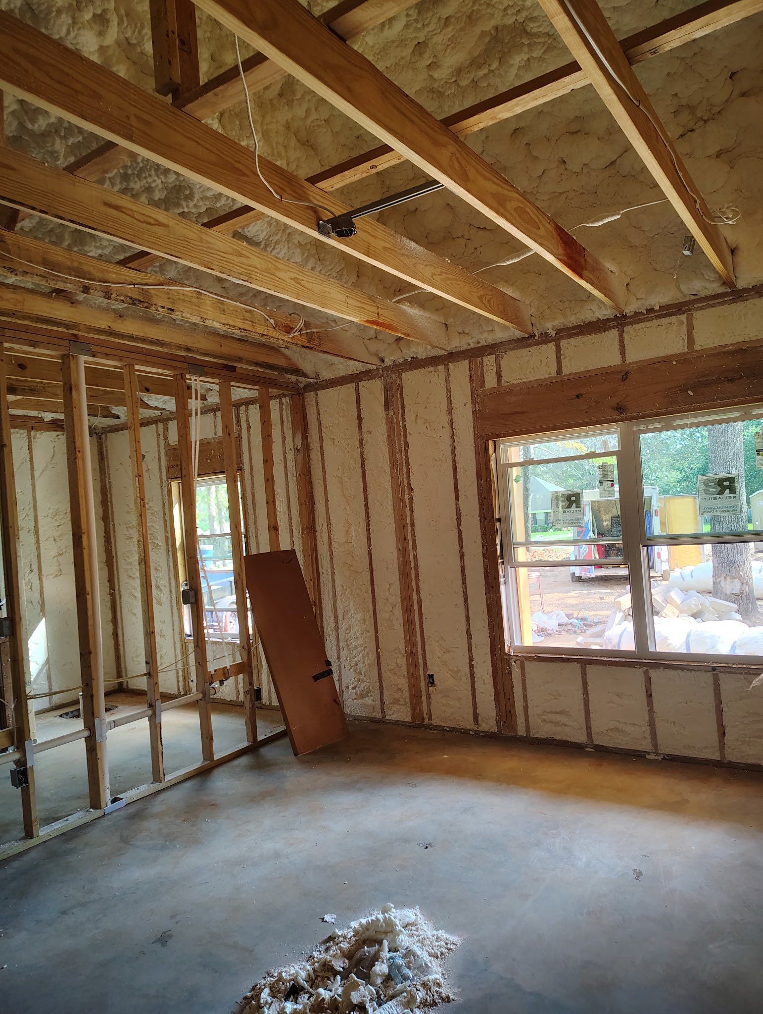 Interior of a room under construction with exposed wooden framing and insulation.