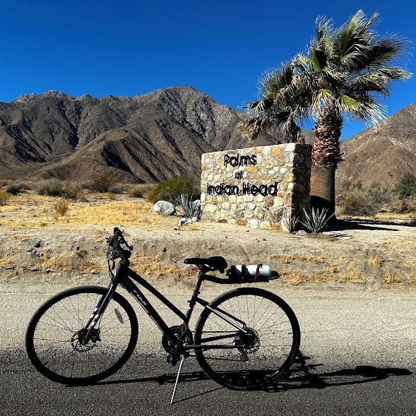 A bicycle is parked in front of a palms of indian head sign