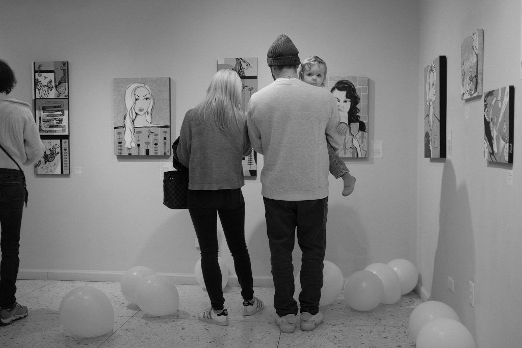 A man and a woman are looking at paintings in a black and white photo.