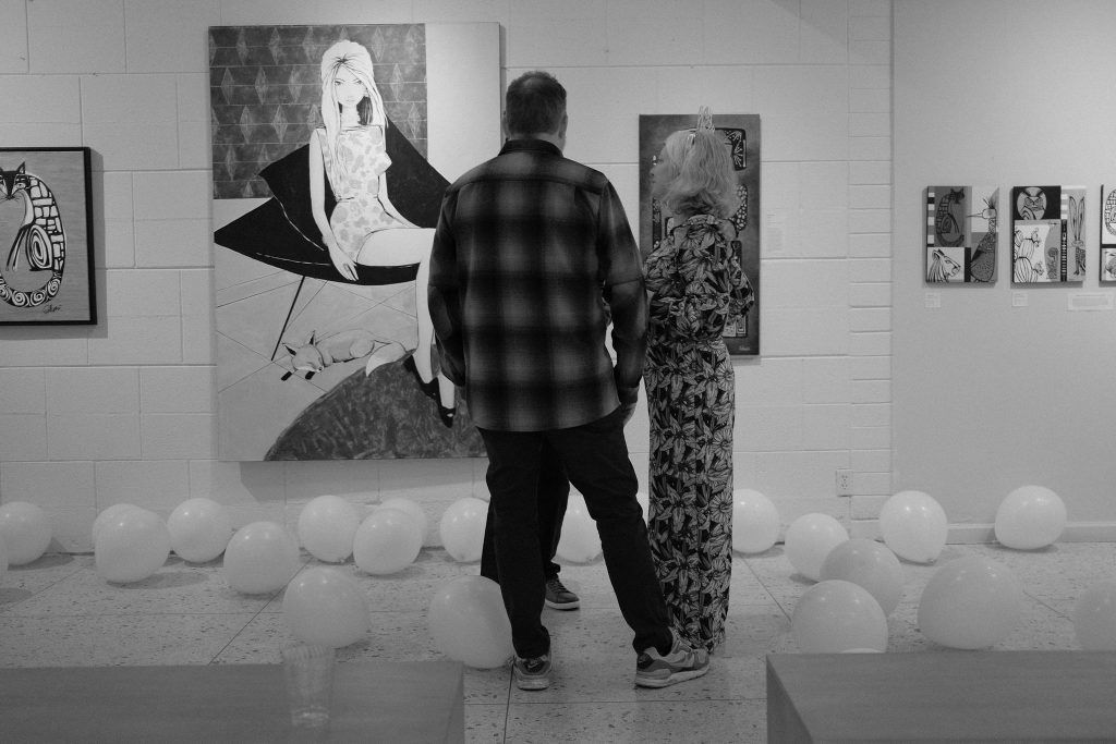 A man and a woman are looking at a painting in a museum.