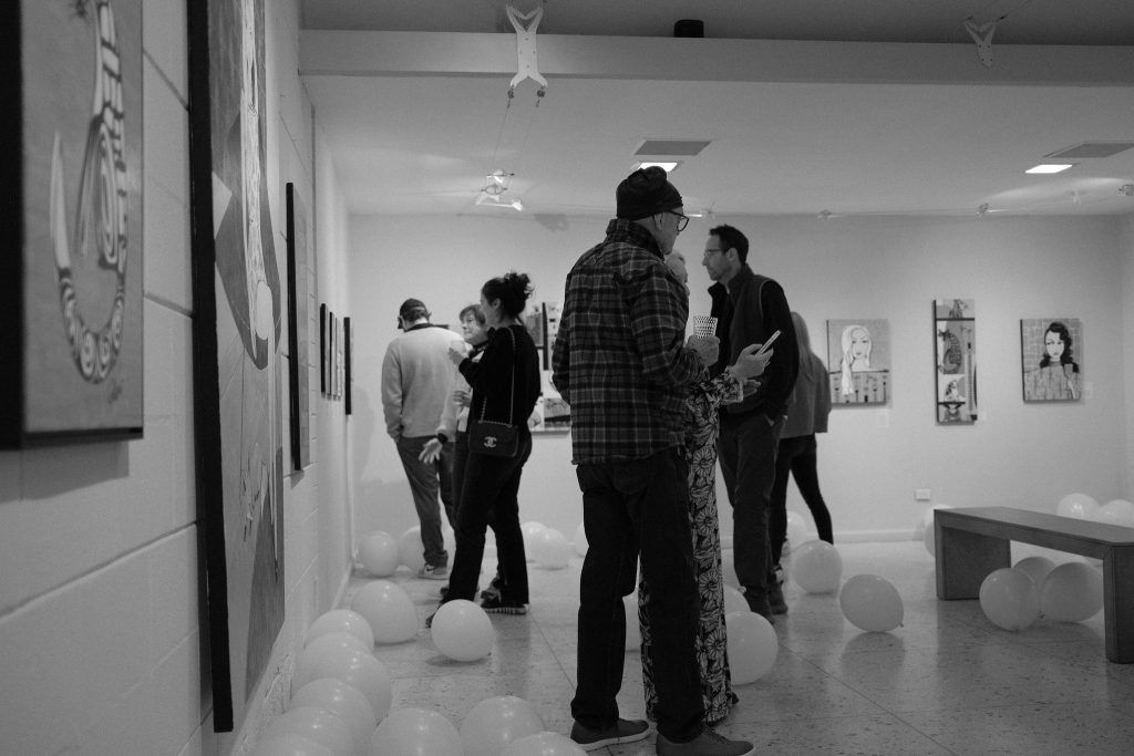 A group of people are standing in a room with balloons on the floor