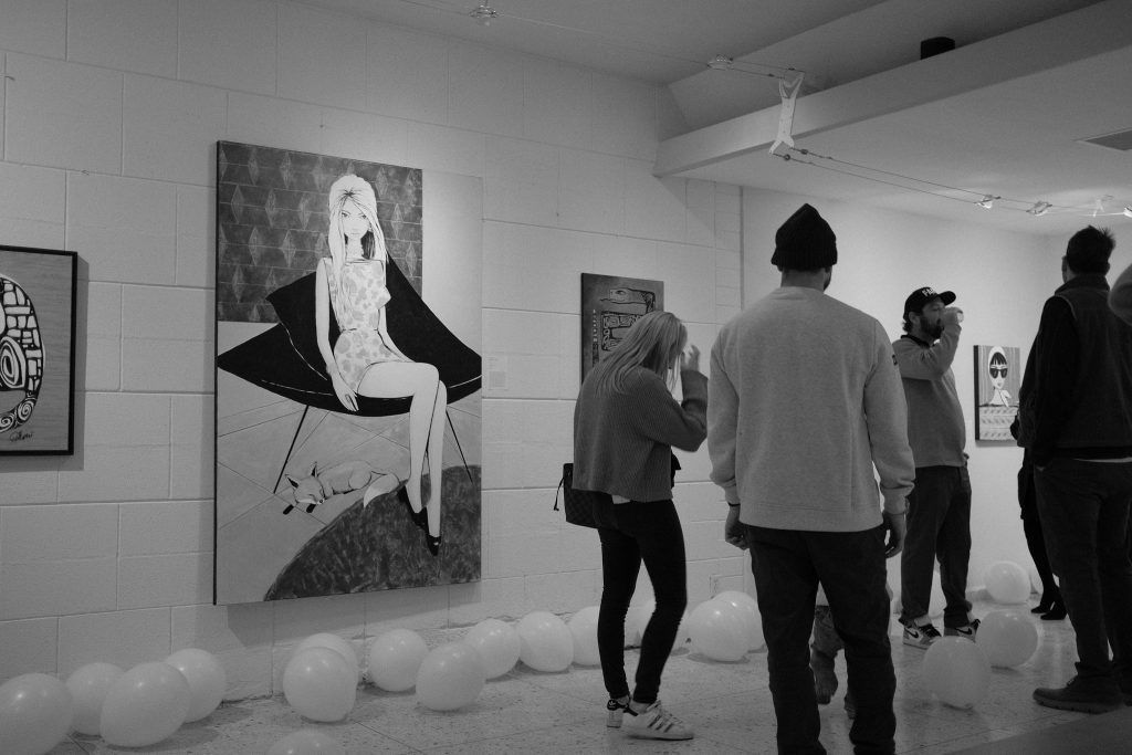 A group of people are looking at paintings in a museum.