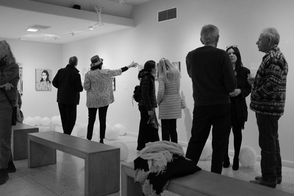 A group of people are standing in a room looking at paintings.