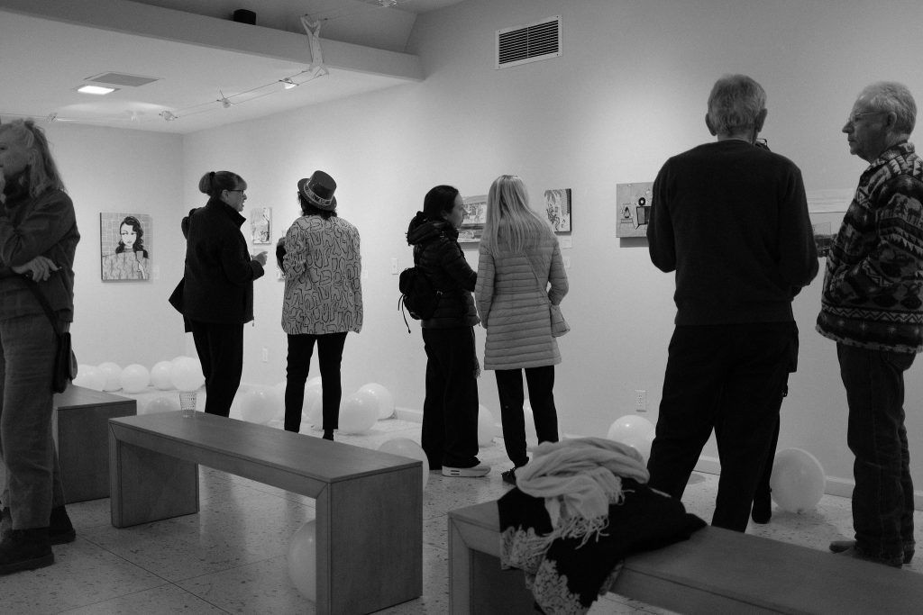 A group of people are standing in a room looking at paintings.