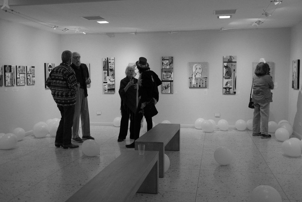 A group of people are looking at paintings in a museum.