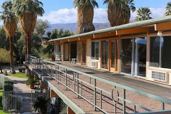 A hotel with a balcony and palm trees in the background.