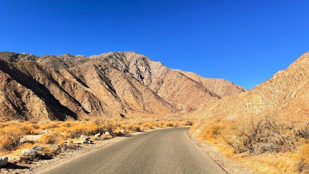 A road in the desert with mountains in the background.