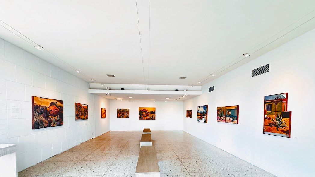 An empty art gallery with paintings on the walls.