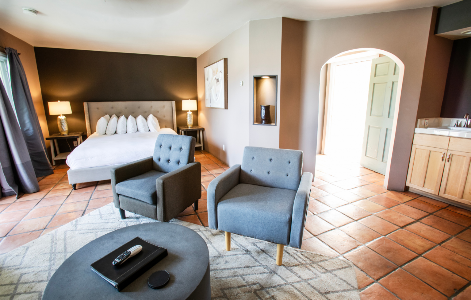 A bedroom with a king size bed , two chairs , a coffee table and a rug.