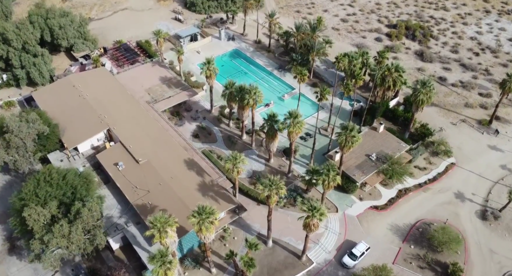 An aerial view of a large swimming pool surrounded by palm trees.