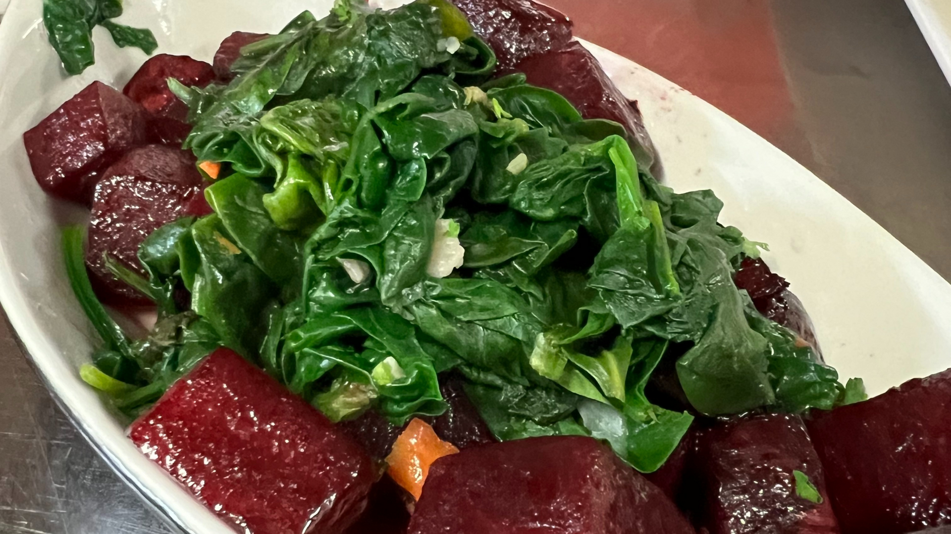 A white plate topped with beets and spinach on a table.