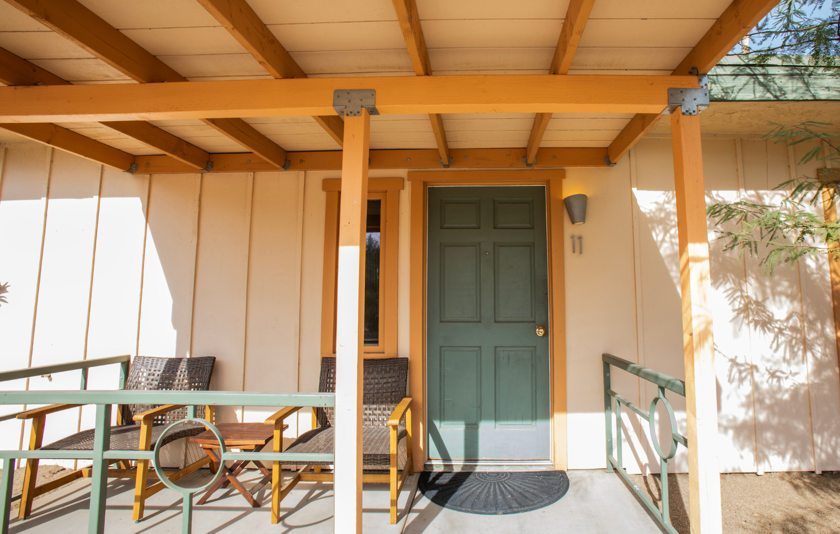 There is a porch with chairs and a green door.