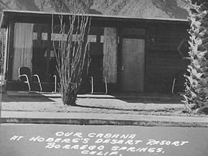 A black and white photo of a house in the desert.