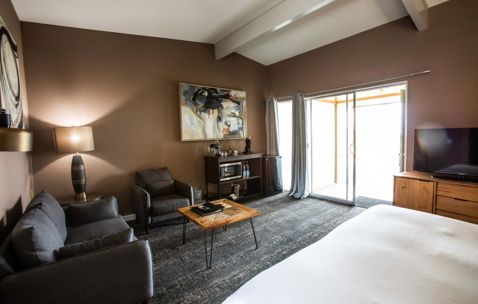 A hotel room with a bed , couch , chairs , table and television.