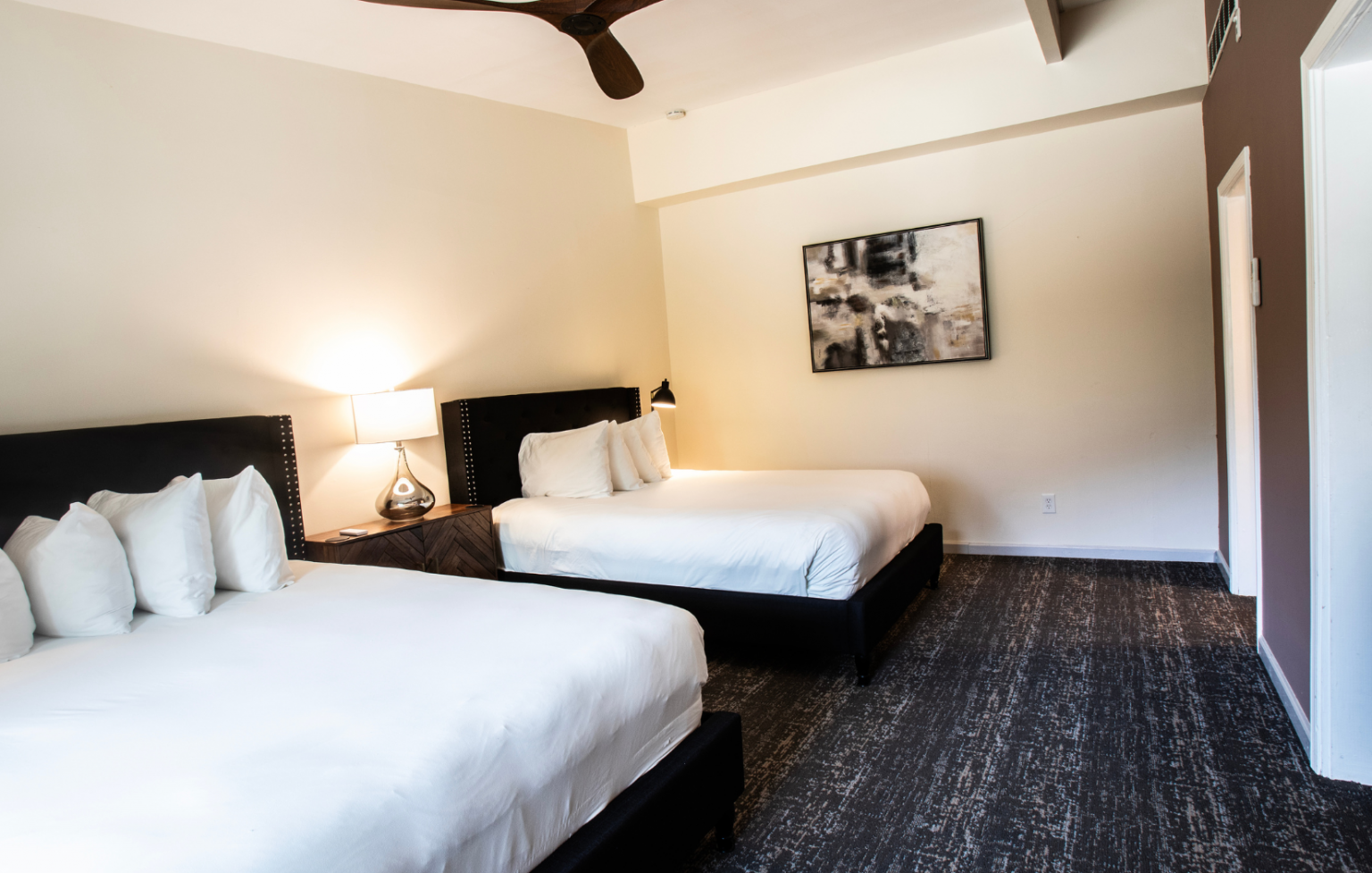A hotel room with two beds and a ceiling fan.