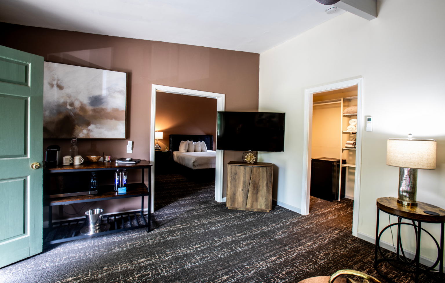 A hotel room with a bed , television , and a painting on the wall.
