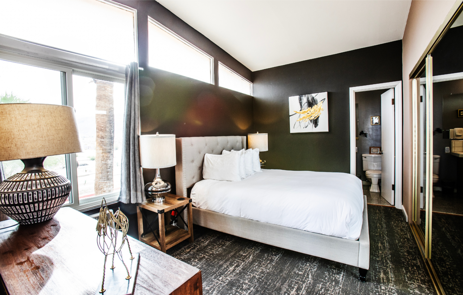 A bedroom with a king size bed , lamps , and a large window.